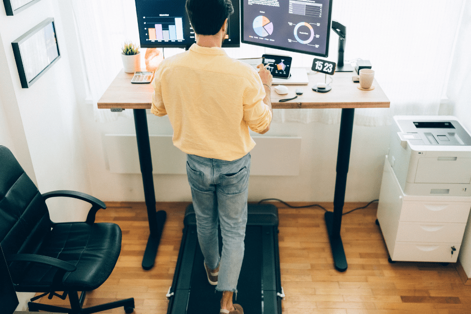 A man walks on treadmill at standup desk in office