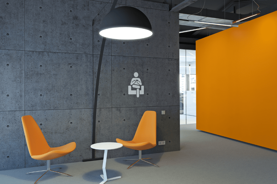 A corner is turned into a private area in an open office by using a cubicle wall as a separator, two chairs and a floor lamp