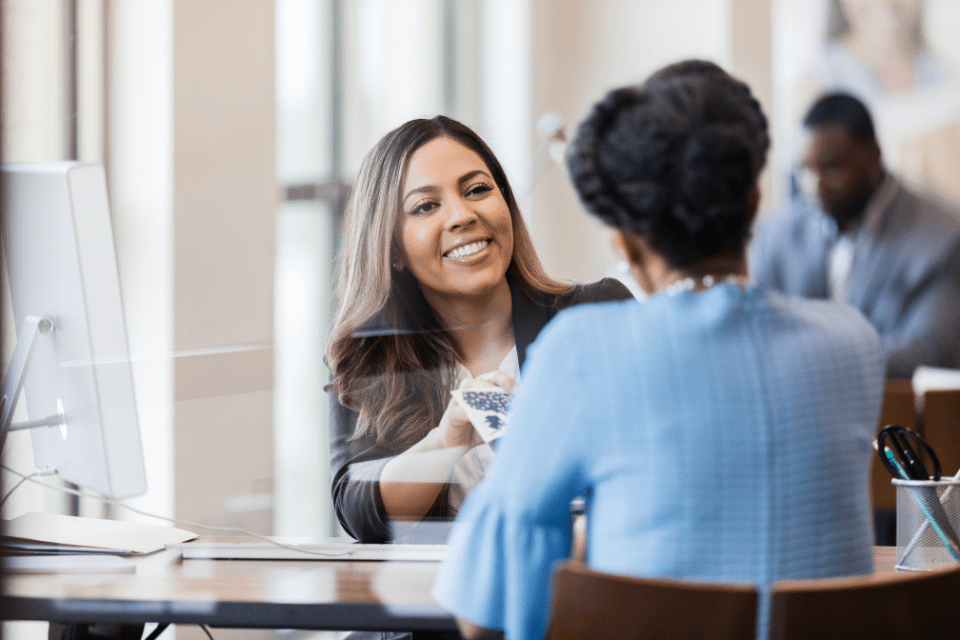 A leader and her direct report talk in an open office