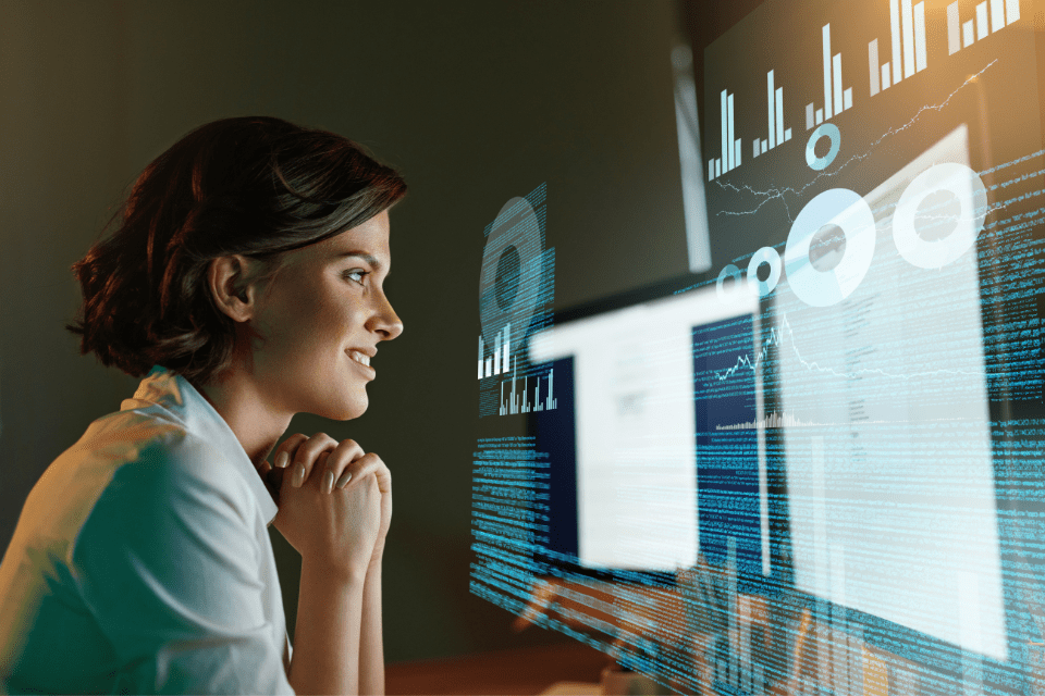 A woman looks at a screen and smiles, energized by a new idea