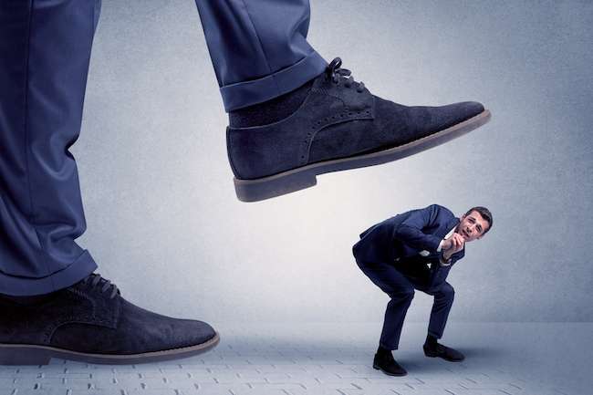 young businessman getting crushed by giant shoe