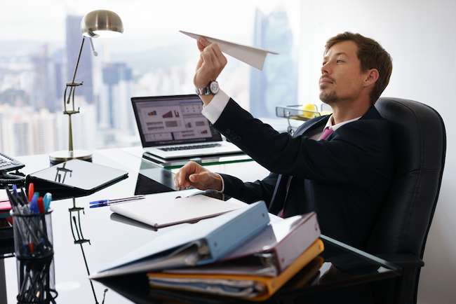a worker procrastinates by making a paper airplane