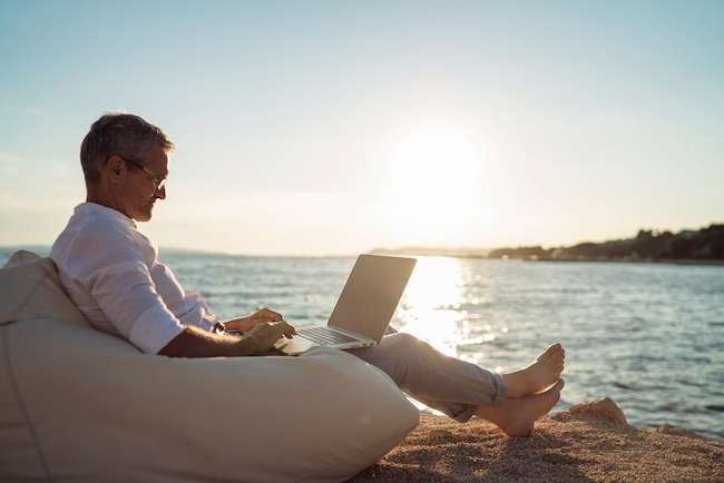 man works on laptop at beach