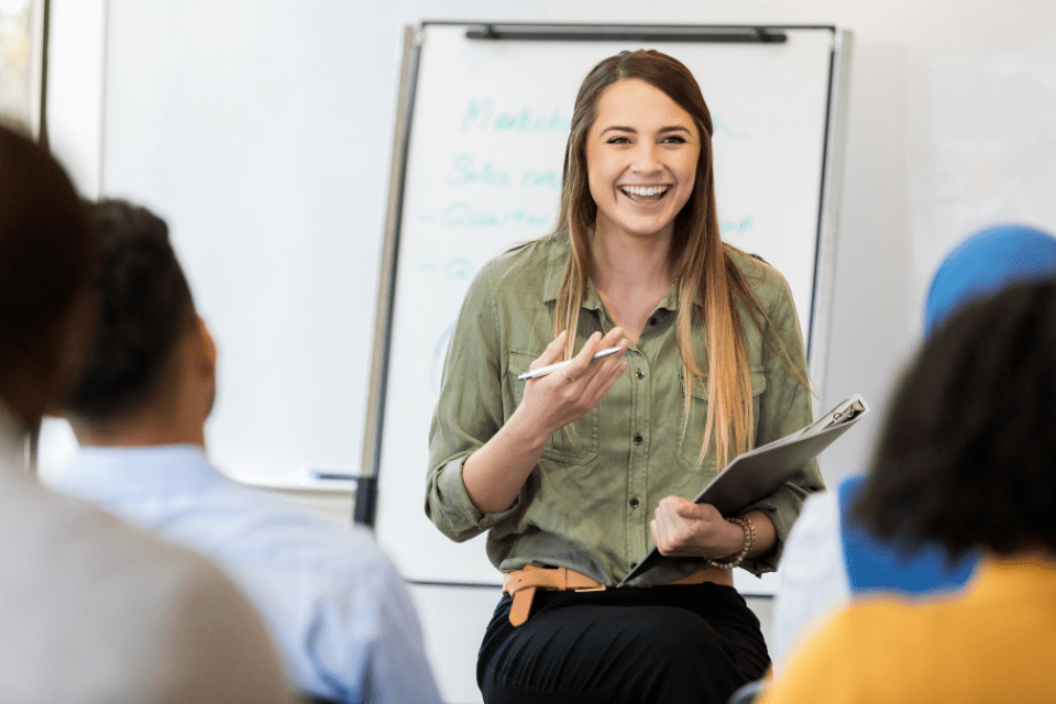 A woman stands in front of a flip chart speaking at a meeting