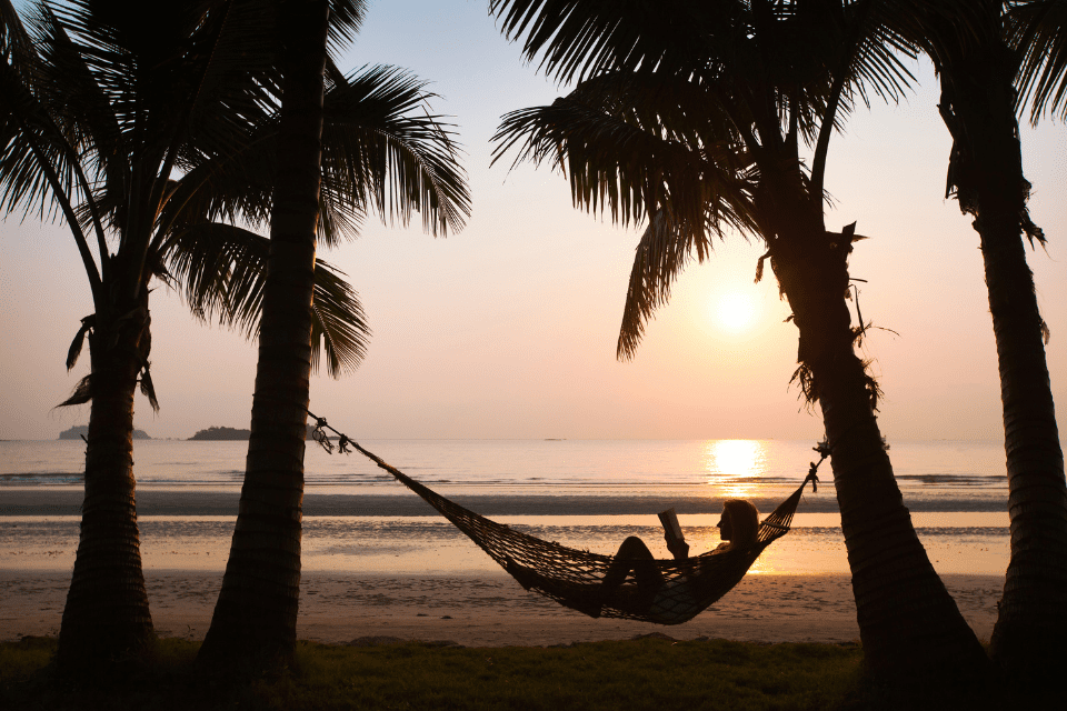 A person lays on a hammock on the beach