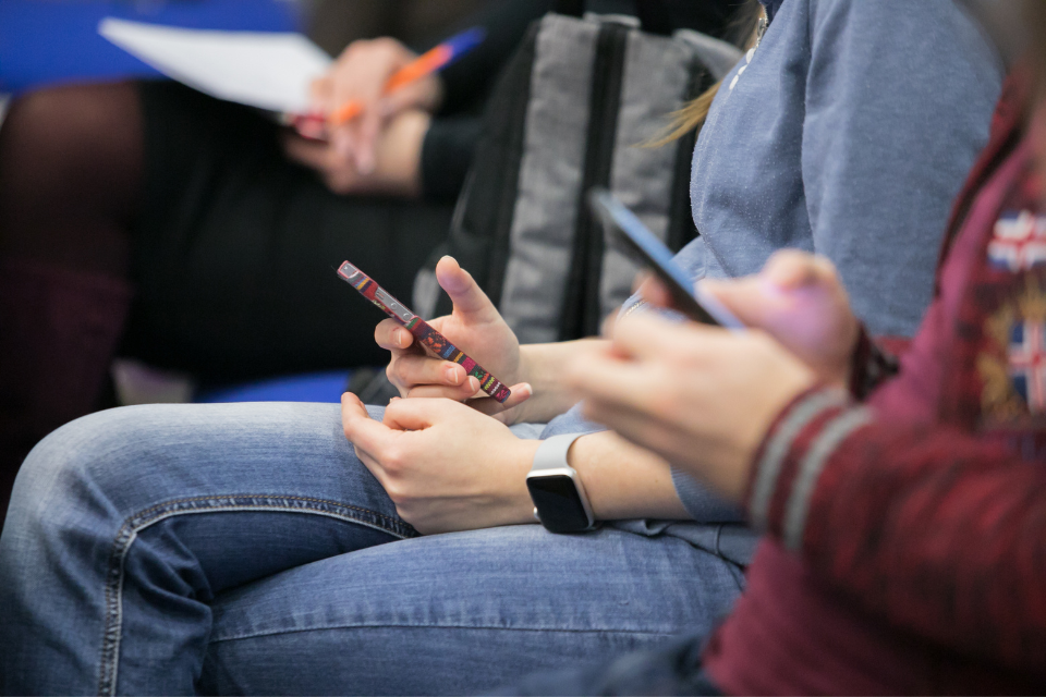 people sitting on a bench looking at their iphones
