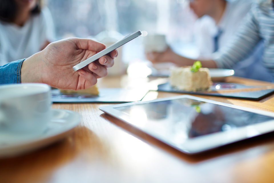a woman looks at her phone while dining at a restaurant with friends