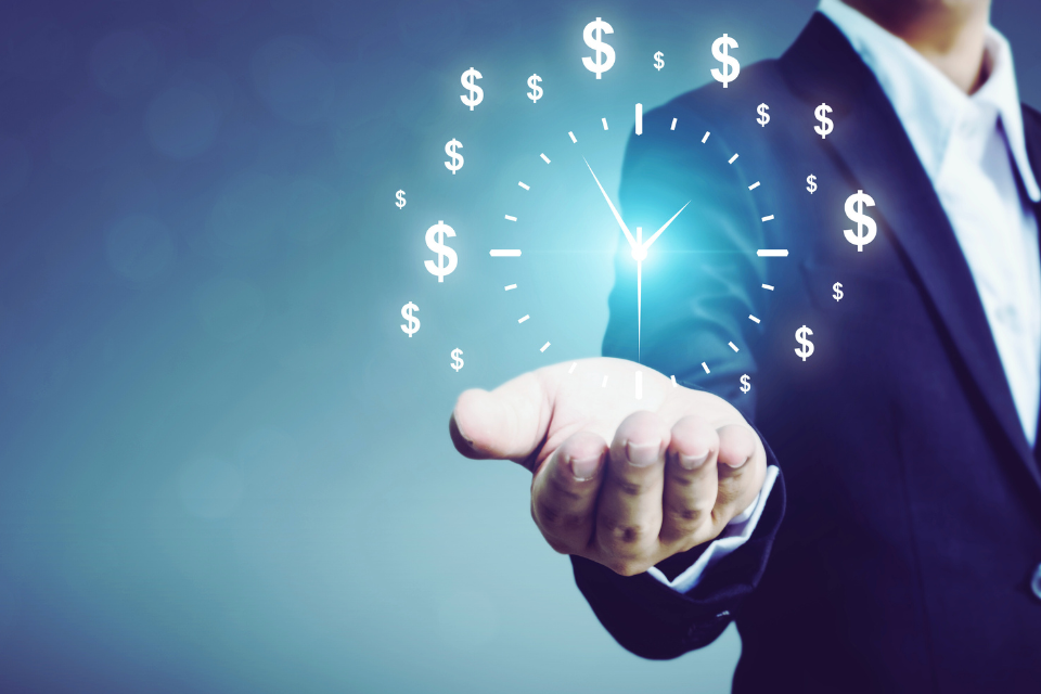 A man in suit holds a clock made of dollar signs