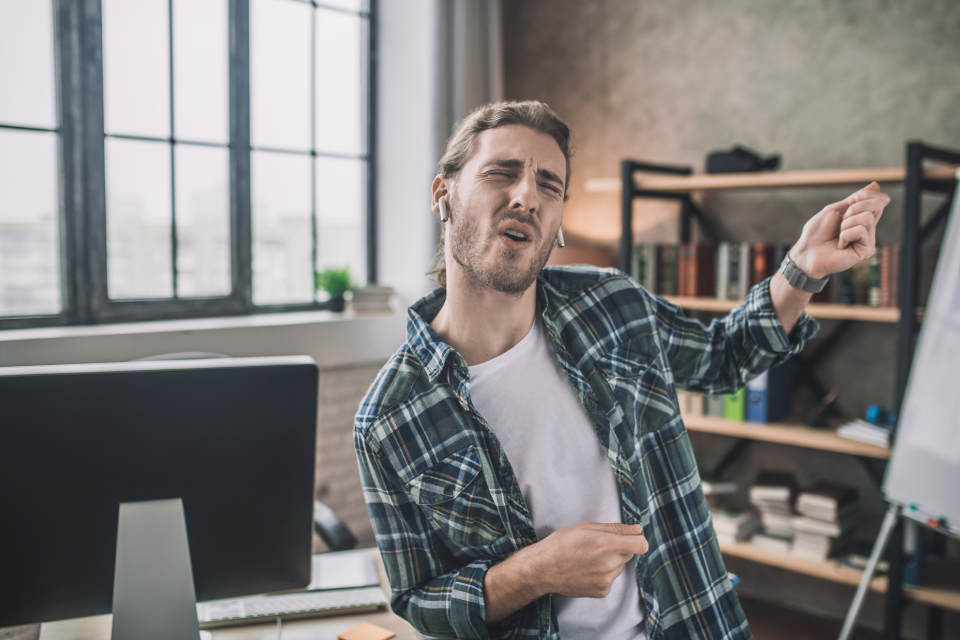 A man dances while sitting at his desk