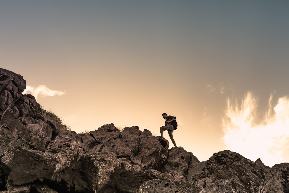 man climbs mountain at sunrise