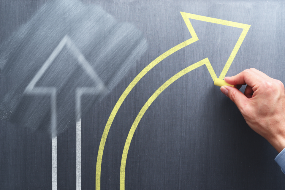 A straight arrow drawn on a chalkboard is partially erased. A curved yellow arrow is drawn on the board.