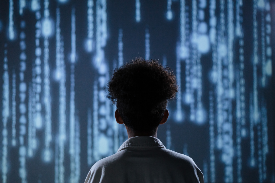 The back of a woman's head as she looks at a giant display of futuristic blue lights