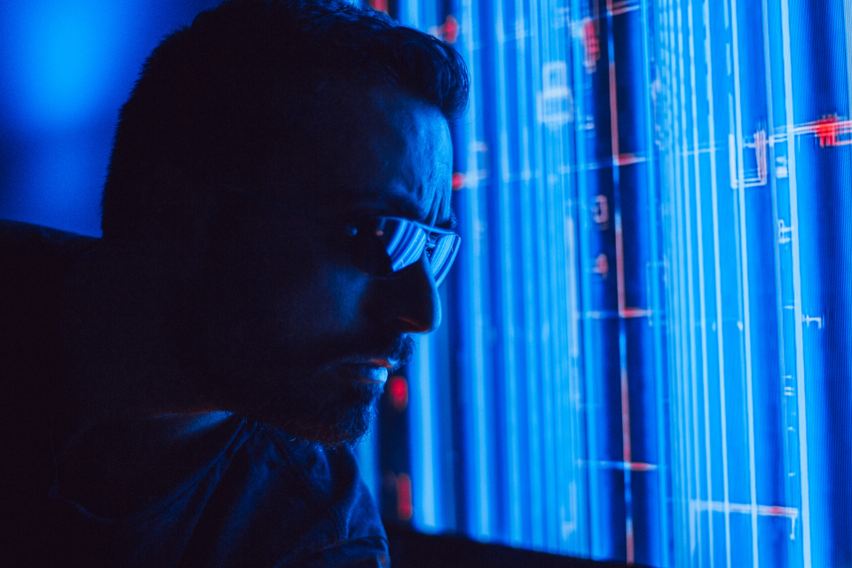Profile of man's head in dark room looking at blue screen