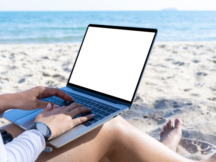A person with laptop open on beach vacation.