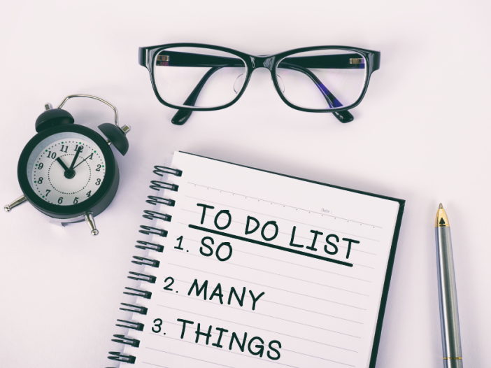 An aerial view of a To Do List that says: "To Do List: 1. So 2. Many 3. Things." There is also a pair of glasses and a small clock.