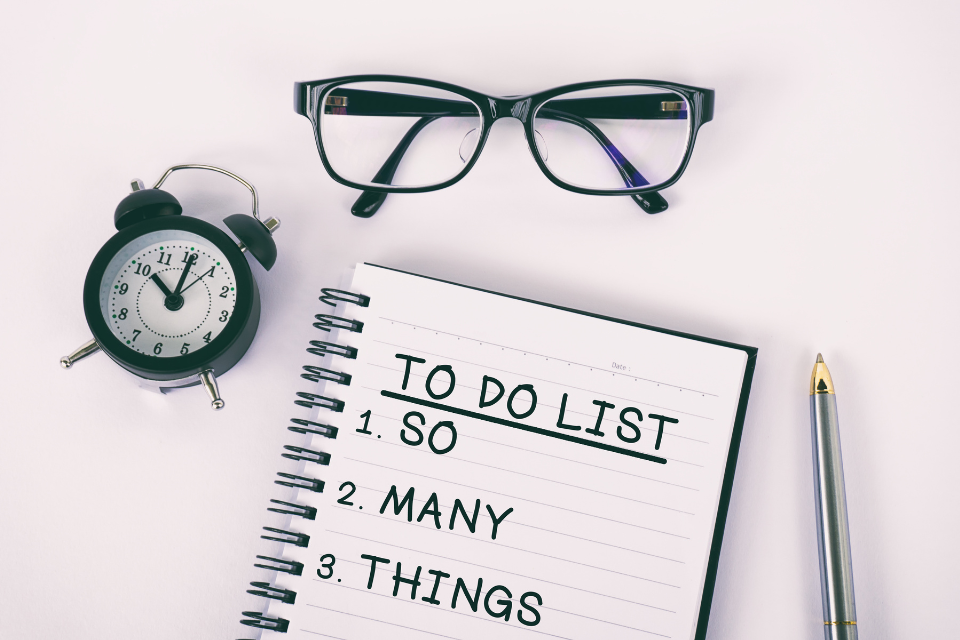 An aerial view of a To Do List that says: "To Do List: 1. So 2. Many 3. Things." There is also a pair of glasses and a small clock.